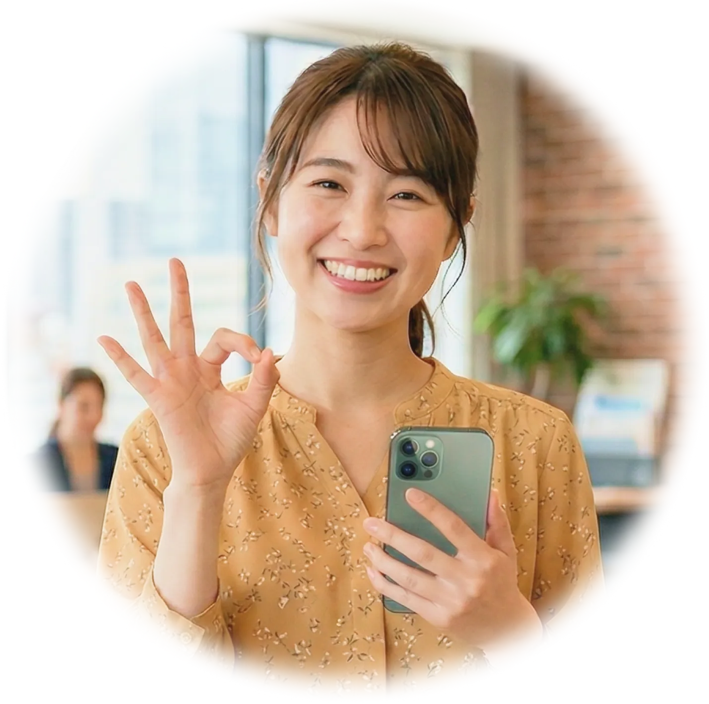 携帯を片手にグーサインする女性